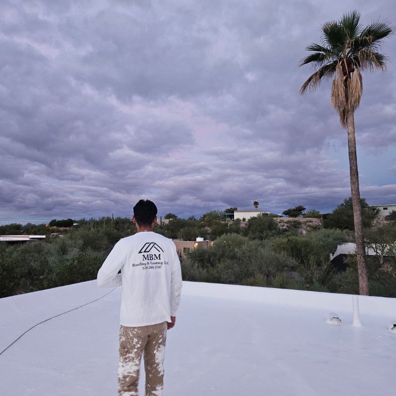 Technician on Completed Roof Coating a Flat Tucson Roof